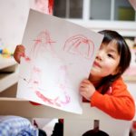 girl holding paper with drawing