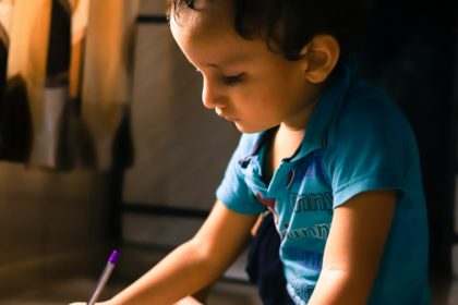 boy writing on white paper