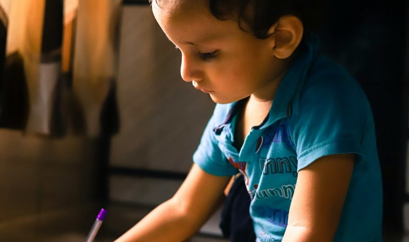 boy writing on white paper