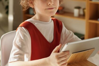 Girl in White and Red Crew Neck T-shirt Using Tablet