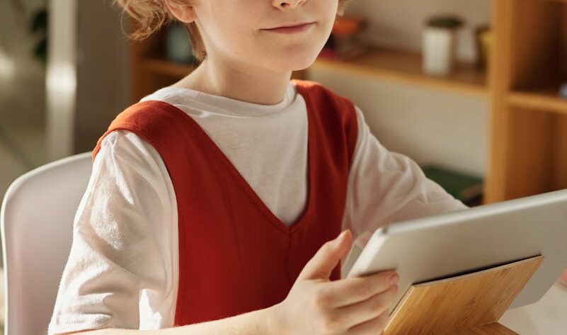 Girl in White and Red Crew Neck T-shirt Using Tablet