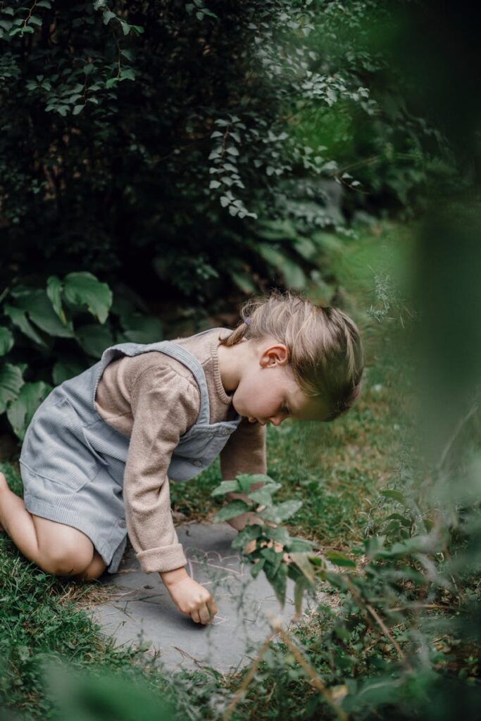 Little girl with chalk drawing on stone in park